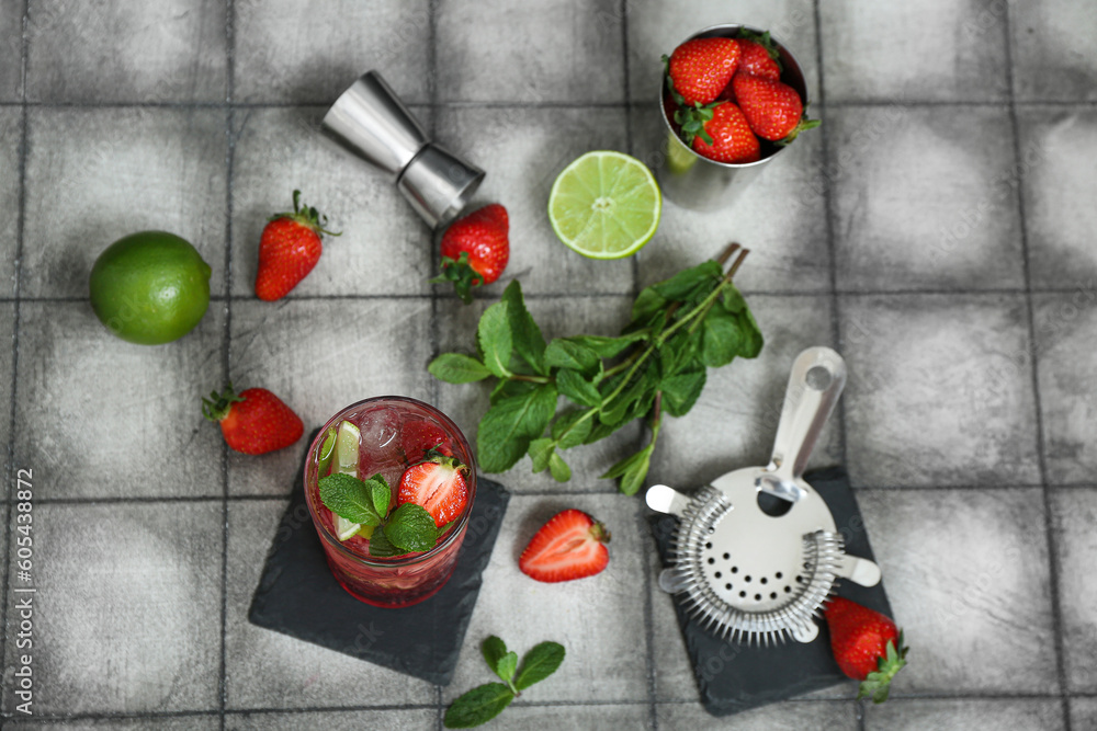 Composition with glass of fresh strawberry mojito and ingredients on tile background