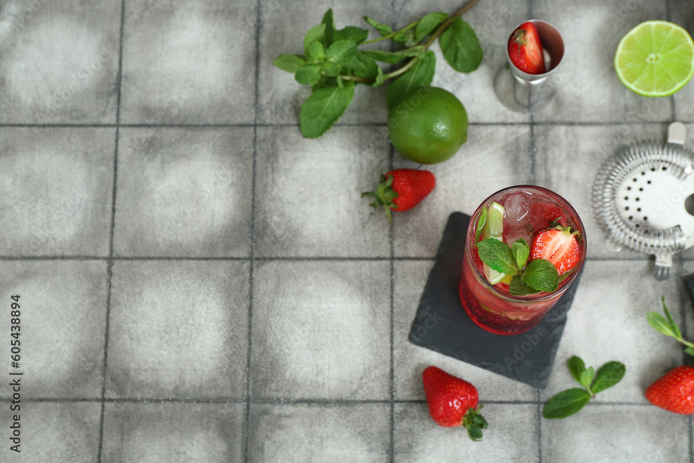 Glass of fresh strawberry mojito on tile background