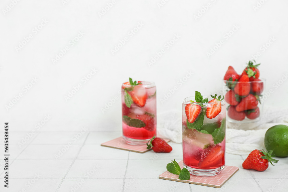 Glasses of fresh strawberry mojito on light tile table