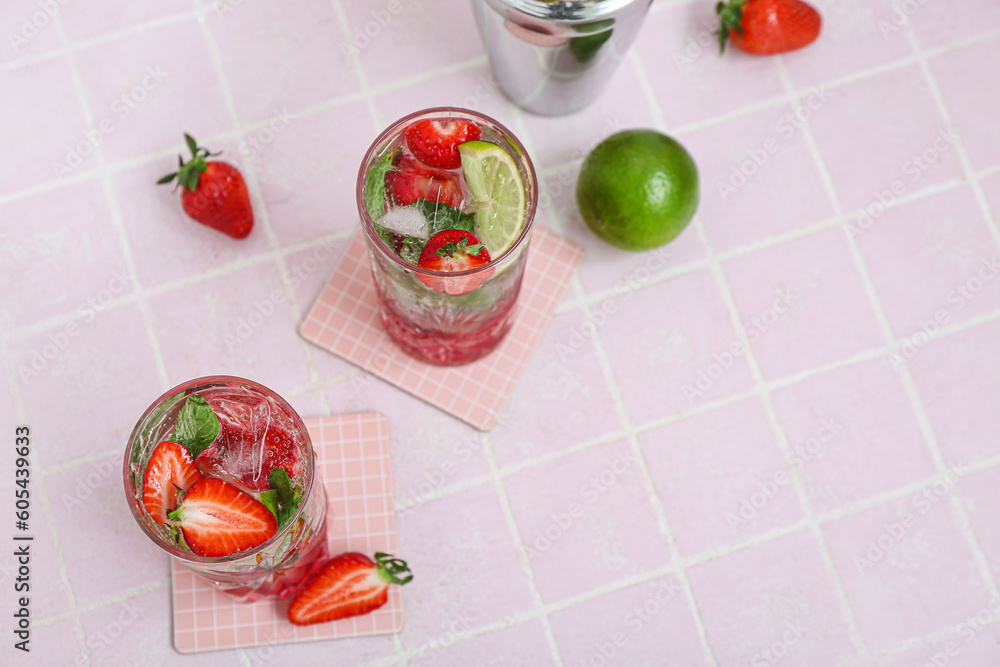 Glasses of delicious strawberry mojito on light tile background