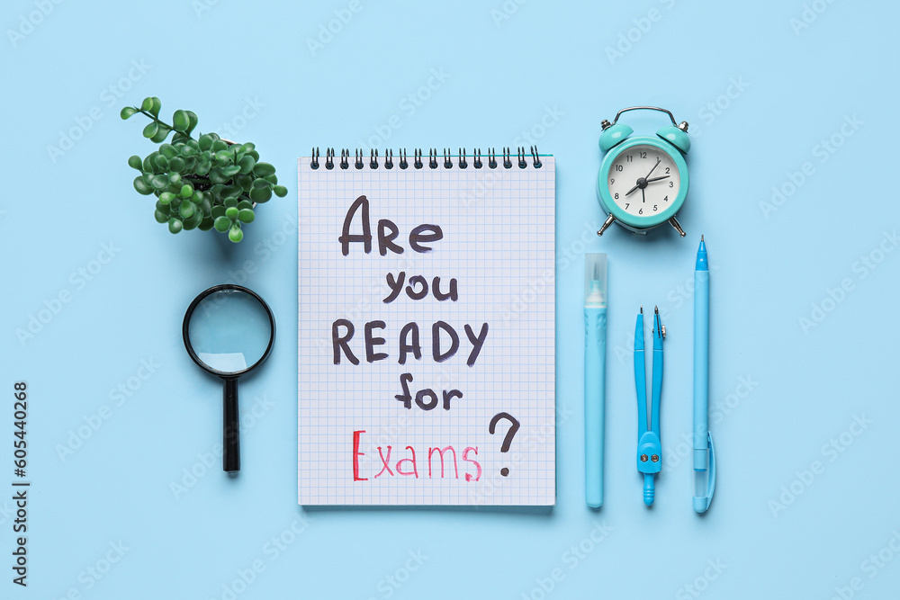 Notebook with question ARE YOU READY FOR EXAMS?, magnifier and alarm clock on blue background