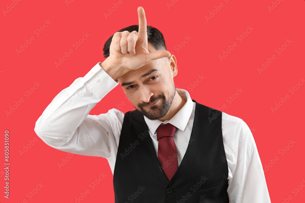 Handsome man showing loser gesture on red background