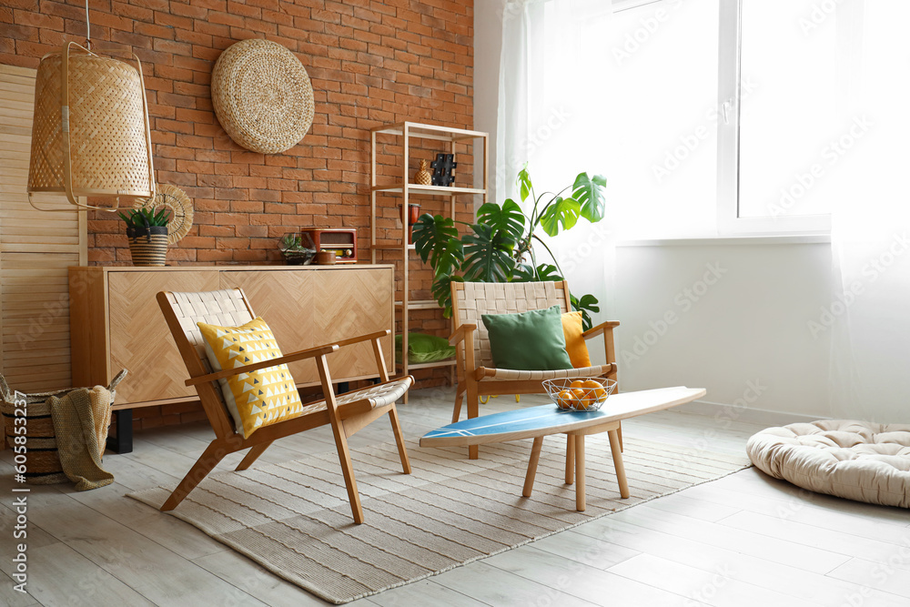 Cozy wooden armchairs with cushions and fruit basket on surfing board in interior of living room