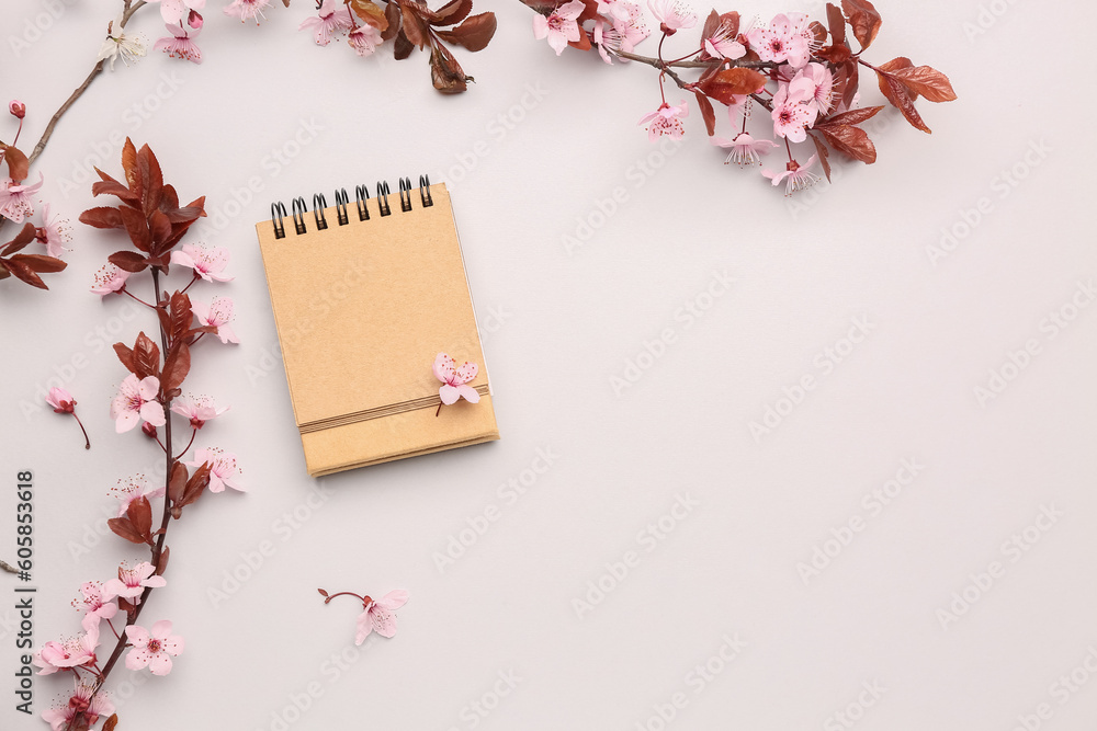 Blooming tree branches with pink flowers and notebook on white background