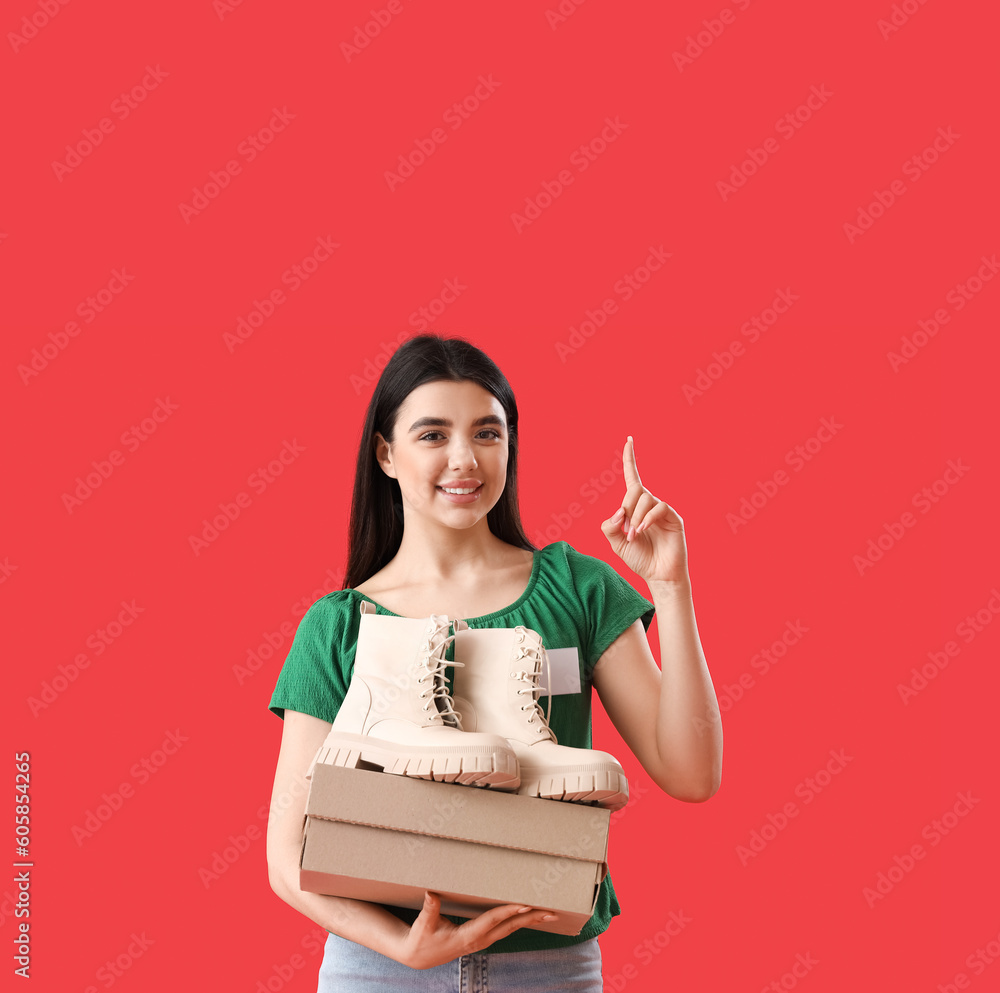 Female seller with stylish boots pointing at something on red background