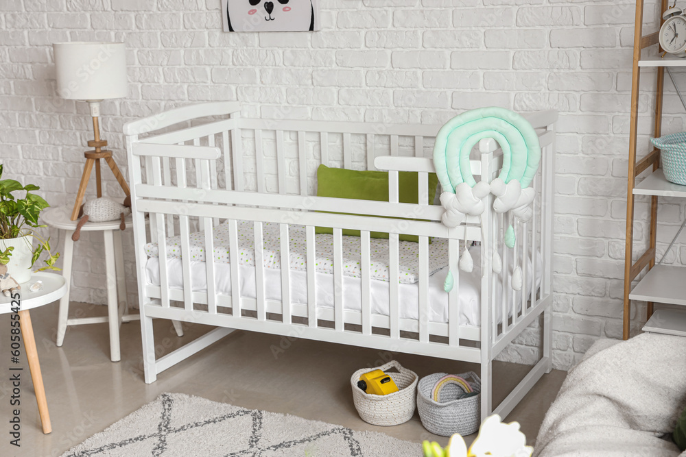 Interior of light bedroom with baby crib