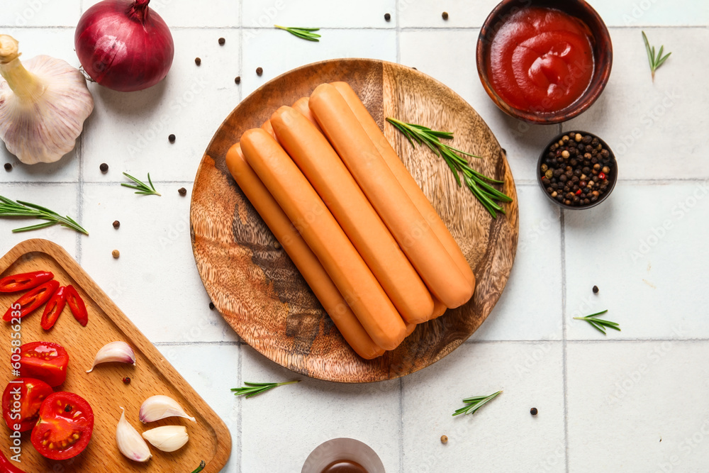 Board and plate of tasty sausages with tomatoes on white tile background