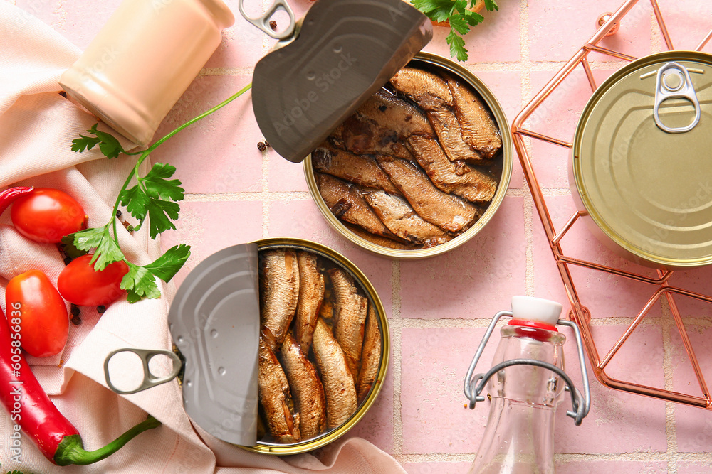 Canned smoked sprats with parsley on pink tile background