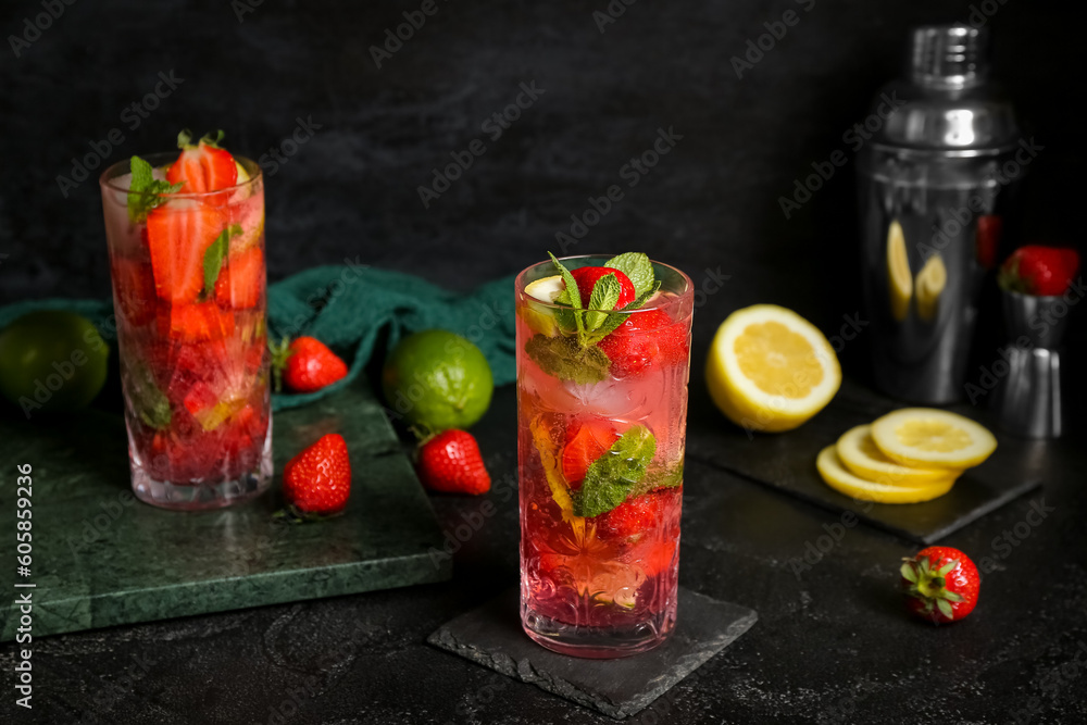 Stands with glasses of fresh strawberry mojito and shaker on black background