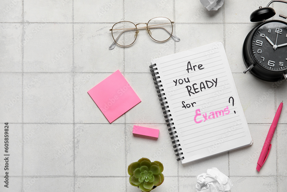 Notebook with question ARE YOU READY FOR EXAM?, alarm clock and eyeglasses on white tile background