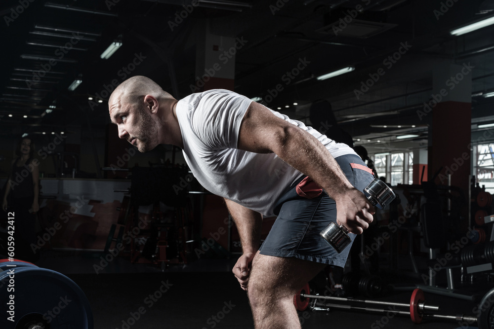 Male bodybuilder engaged with dumbbells in the gym