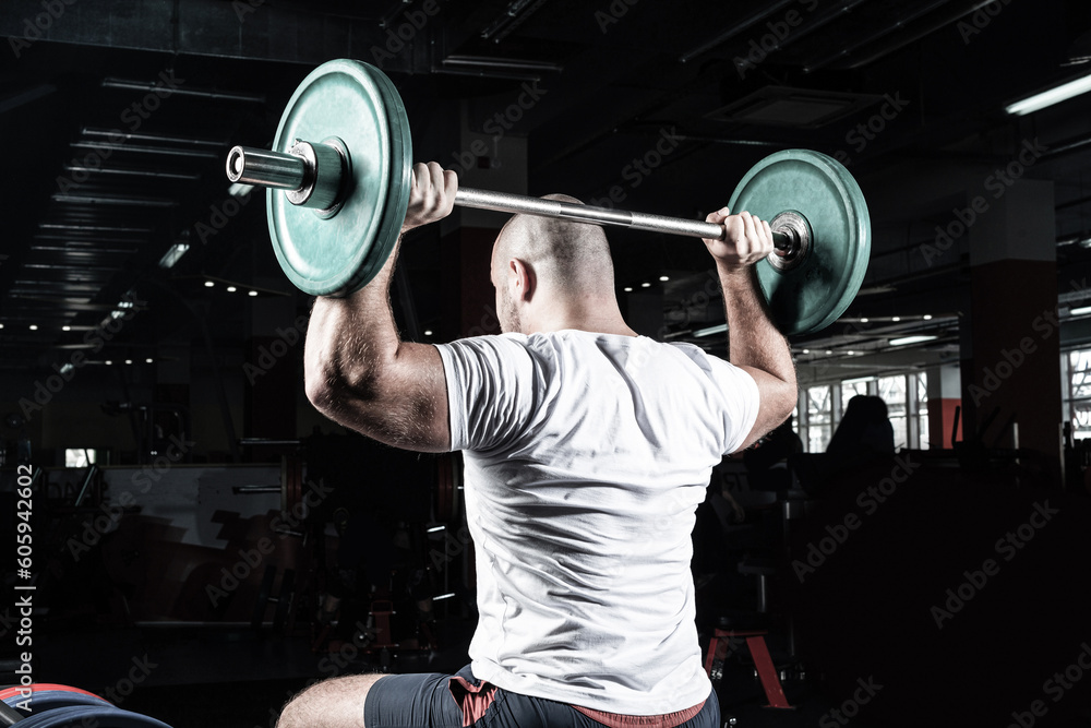 Male athlete lifts the barbell