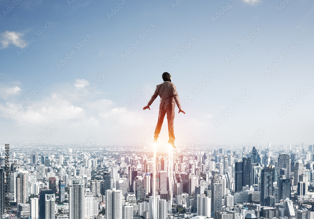 Businessman in suit and aviator hat flying in sky