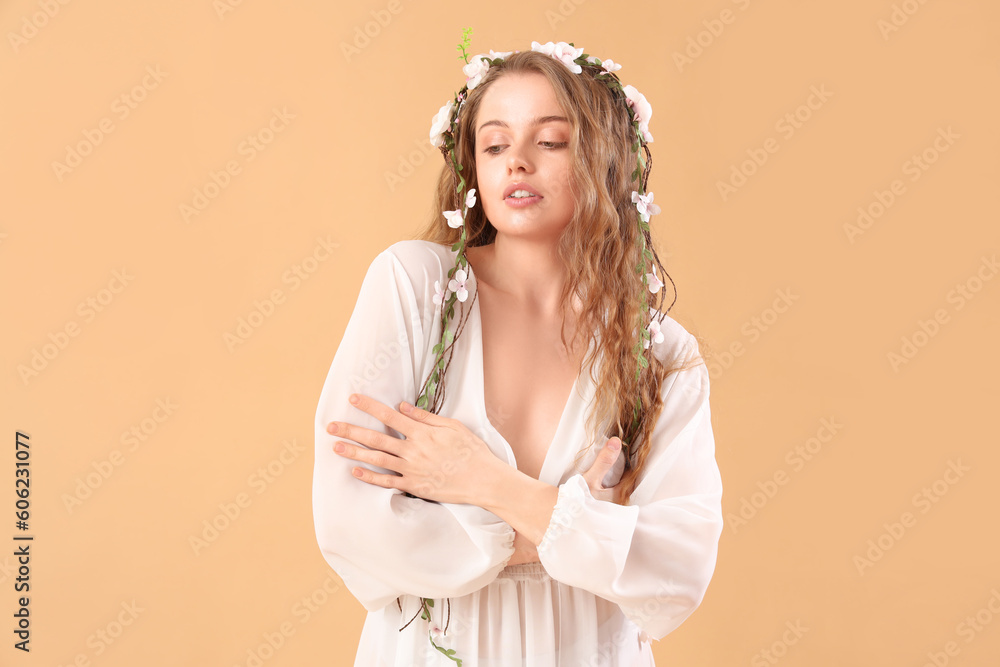 Beautiful young woman with flowers in her hair on beige background. Summer solstice