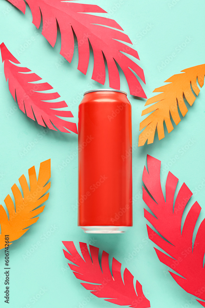 Composition with can of fresh soda and paper leaves on turquoise background