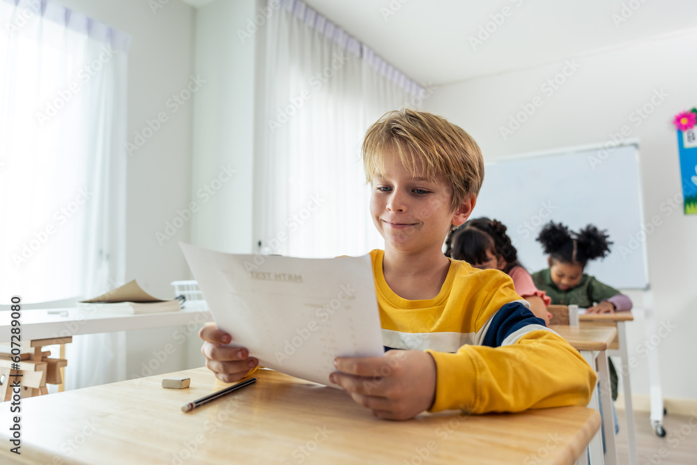 Caucasian young boy student doing an exam test at elementary school. 