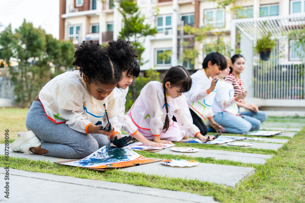 Group of student coloring on painting board outdoors in school garden. 