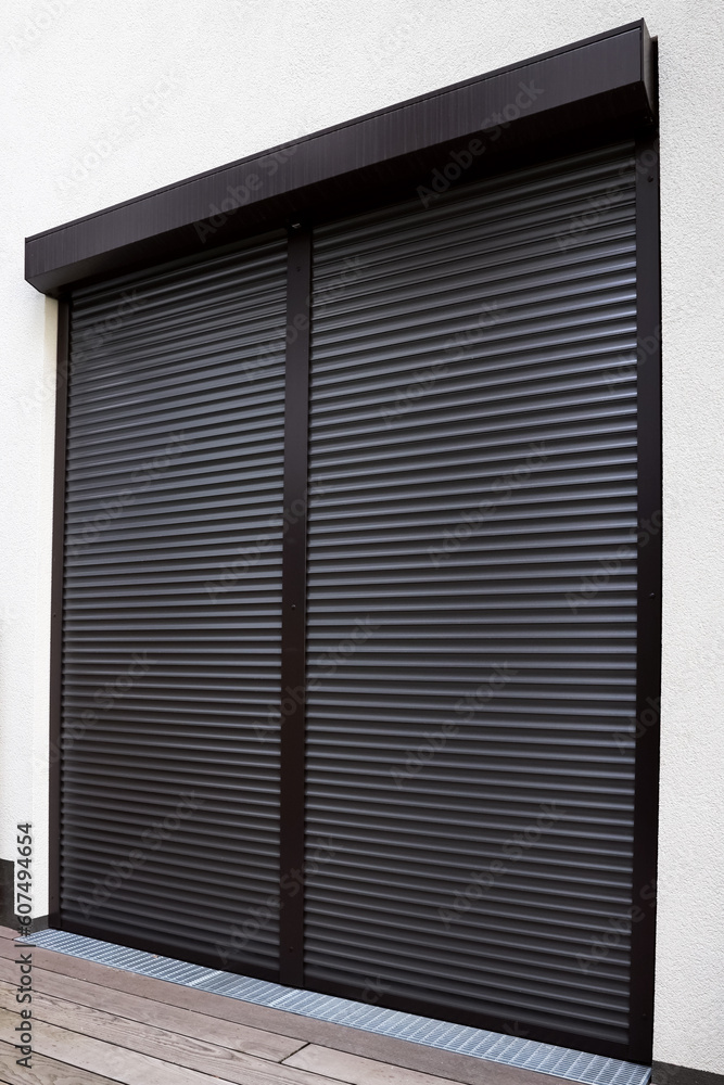 View of building with big windows and black roller shutters outdoors