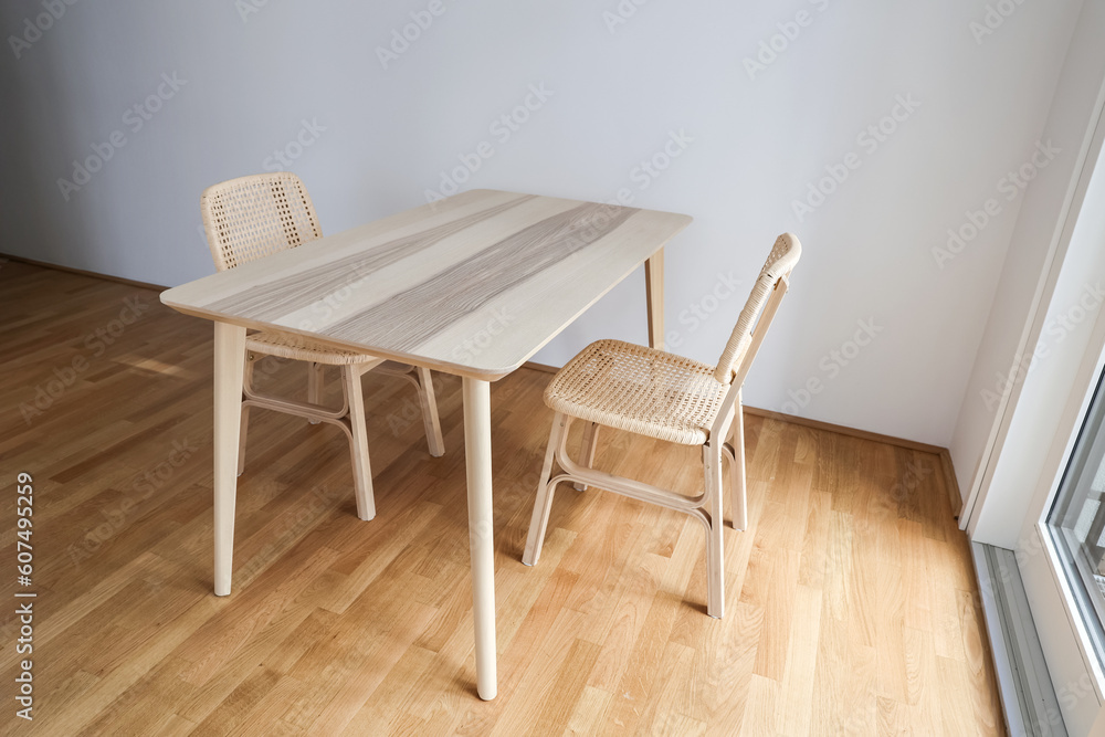 Wooden dining table with wicker chairs in light room