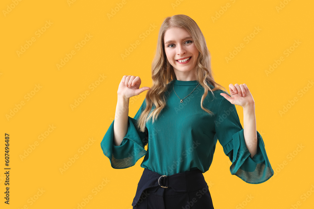 Young woman pointing at herself on yellow background