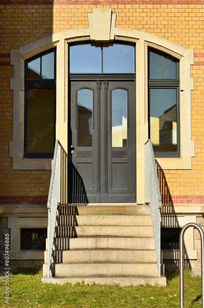 View of brick building with black wooden door and steps