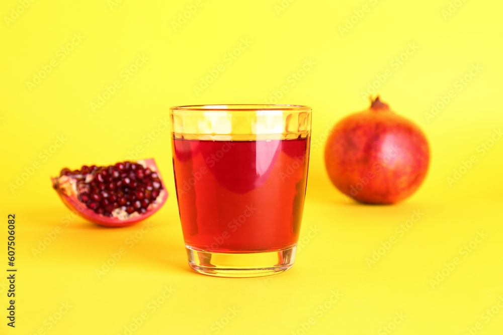 Glass of fresh pomegranate juice on yellow background