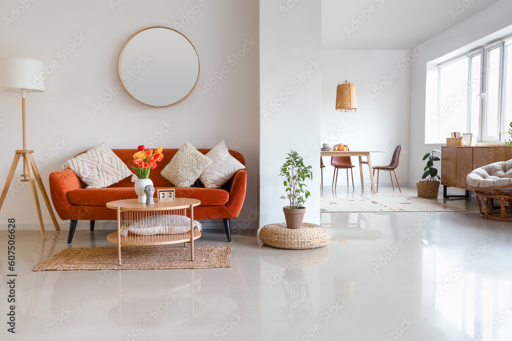 Interior of stylish living room with cozy sofa, mirror and tulip flowers on coffee table