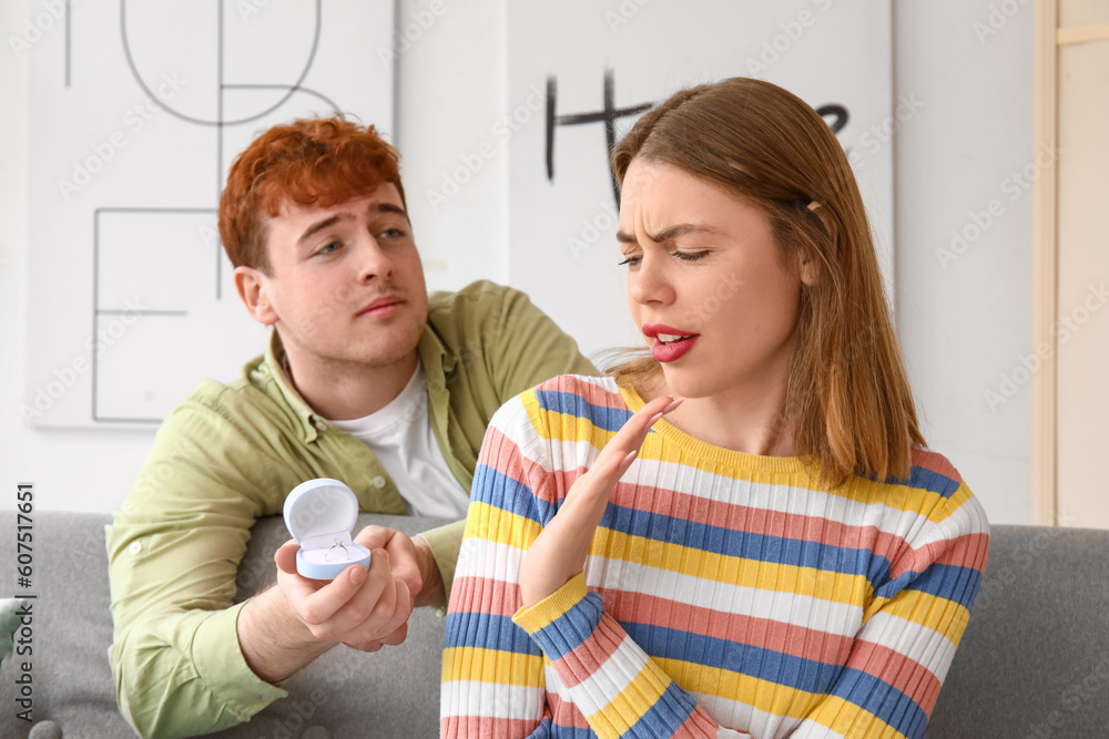 Young woman rejecting marriage proposal from her boyfriend at home