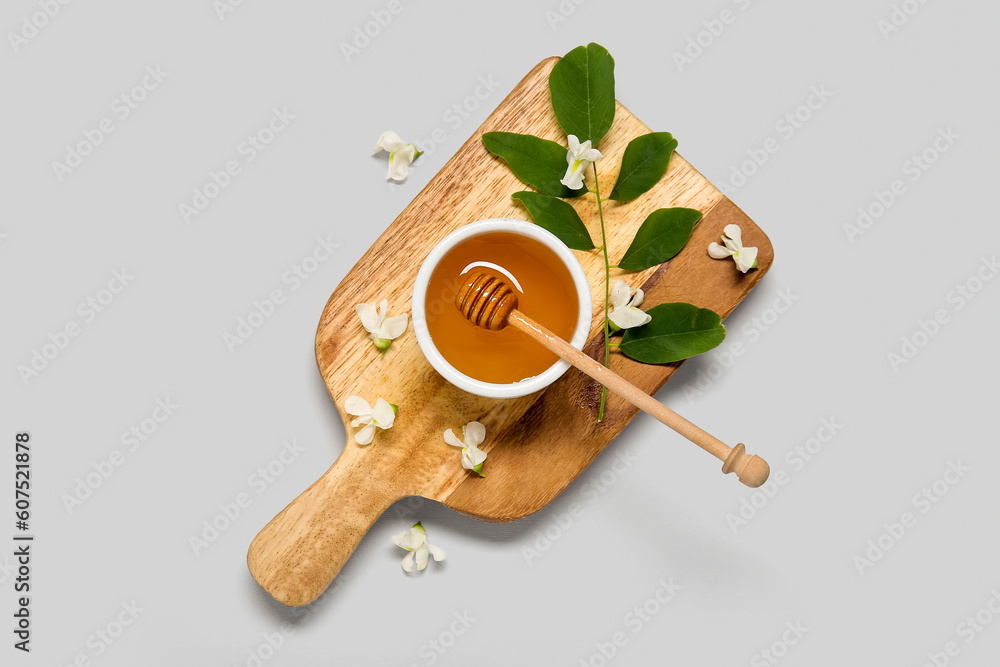 Bowl of honey with flowers of acacia and branch on white background