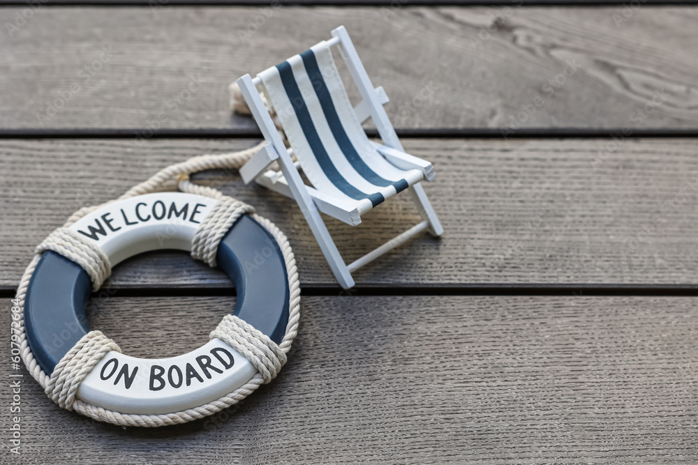 Toy sun lounger and ring buoy on grey wooden background