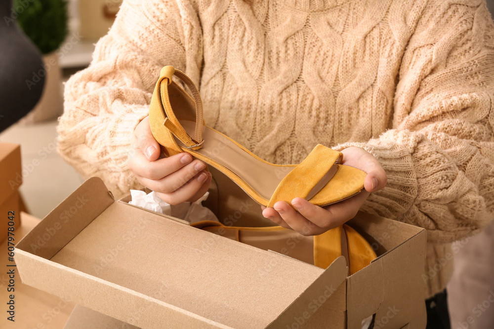 Woman taking out yellow suede shoes from  box in room