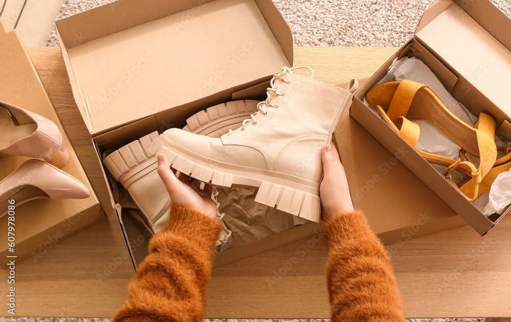 Woman taking beige boots out of box in room