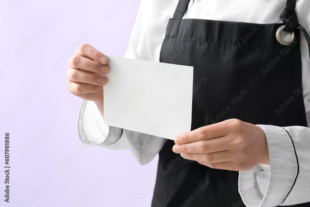 Female chef holding blank card on purple background, closeup