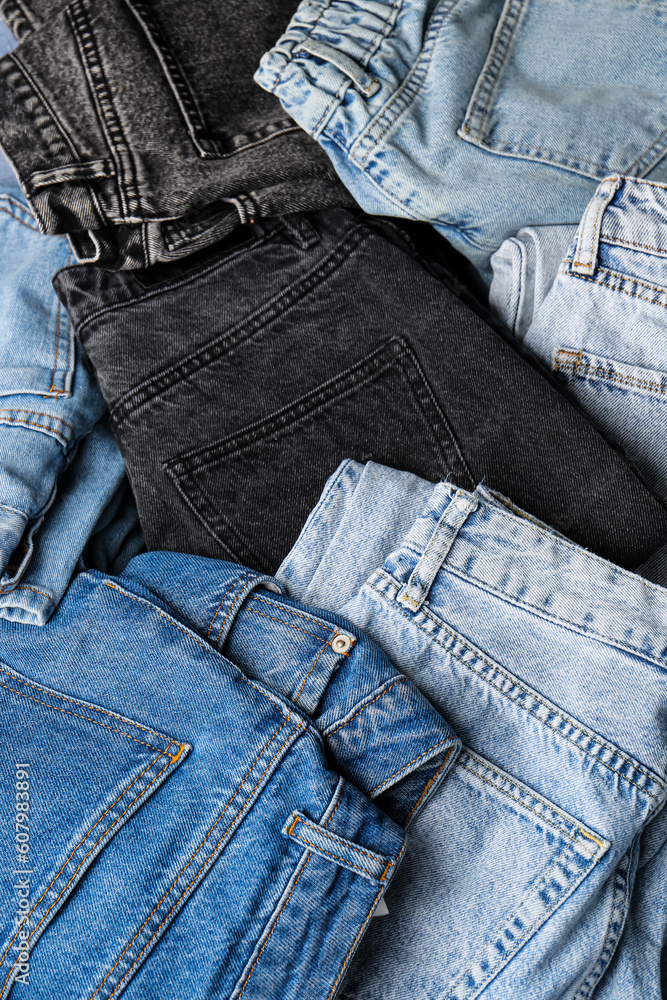 Different stylish denim jeans as background, closeup