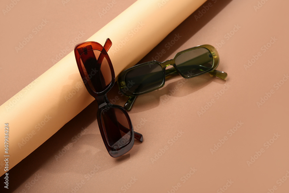 Stylish sunglasses on brown background