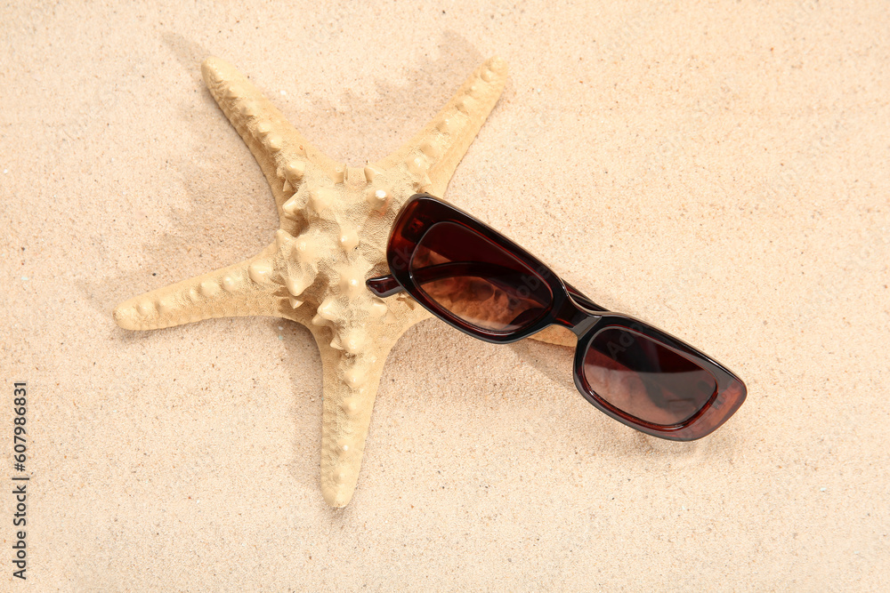 Stylish sunglasses and starfish on beige background