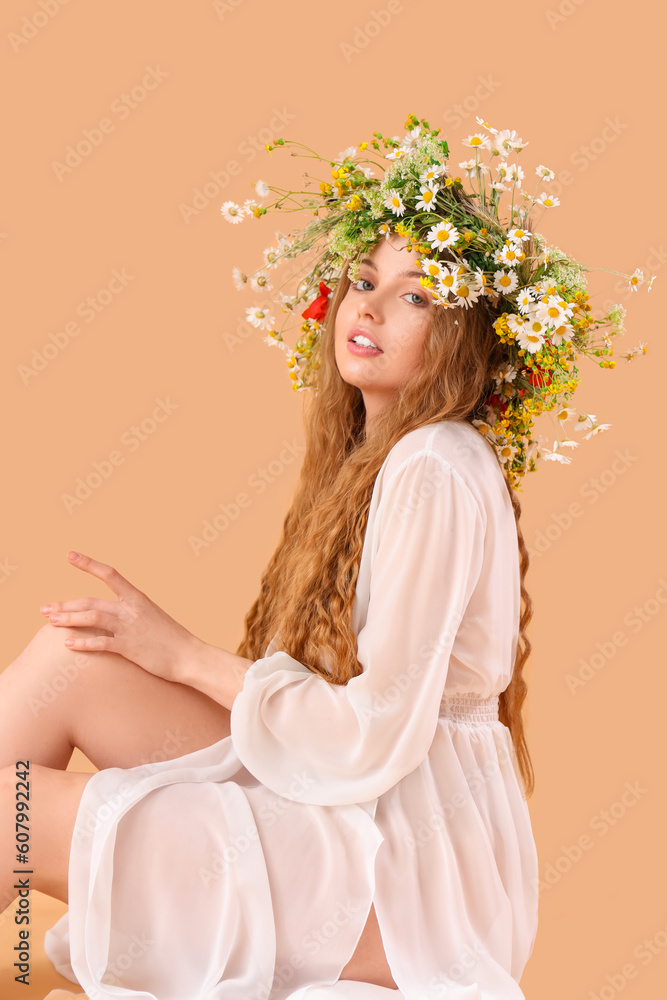 Beautiful young woman in flower wreath on beige background. Summer solstice