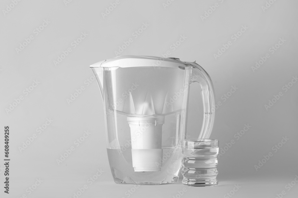 Water filter jug with glass on light background