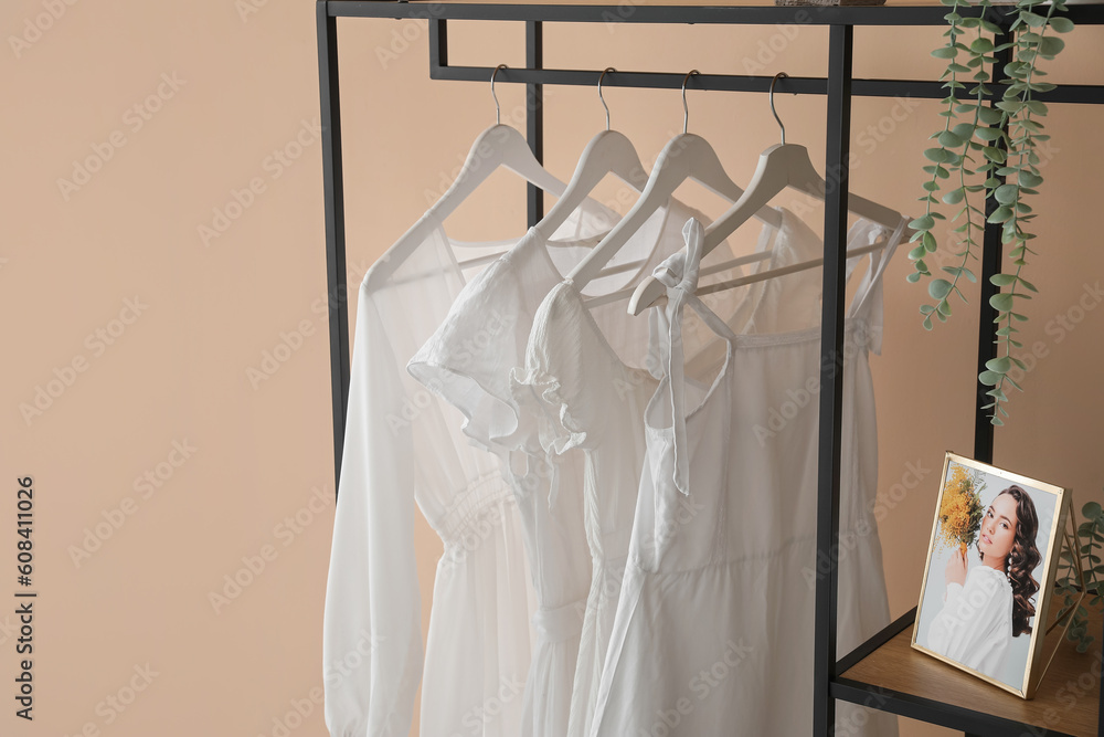 Shelving unit with clothes and photo frame near beige wall