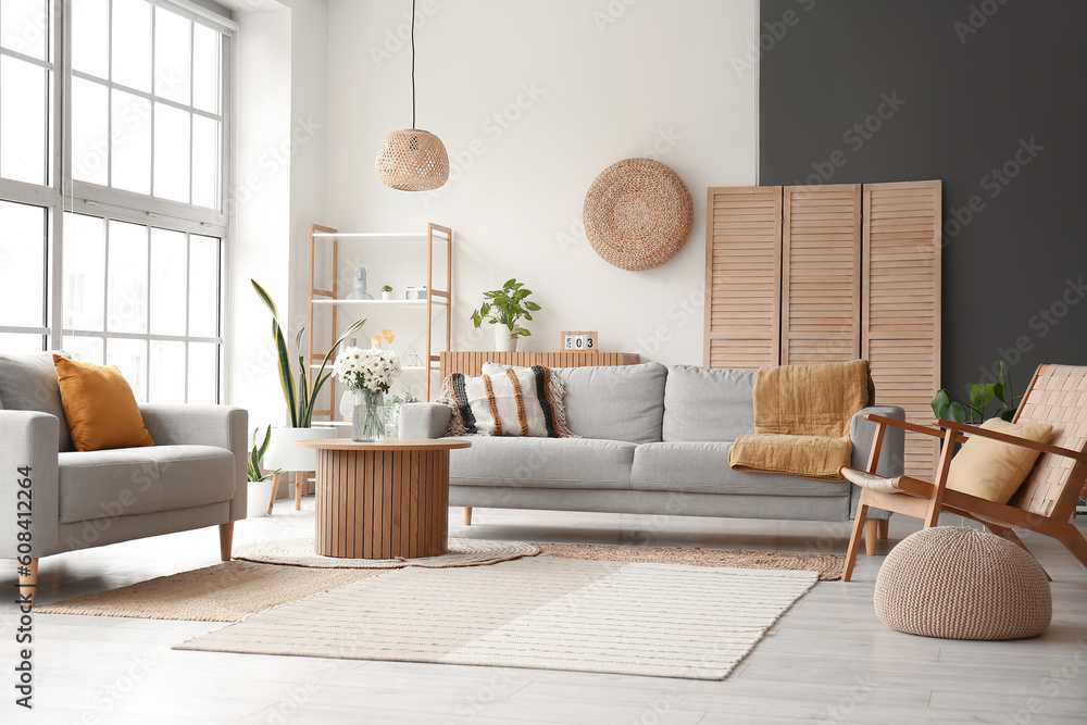 Interior of light living room with grey sofas, wooden armchair and coffee table