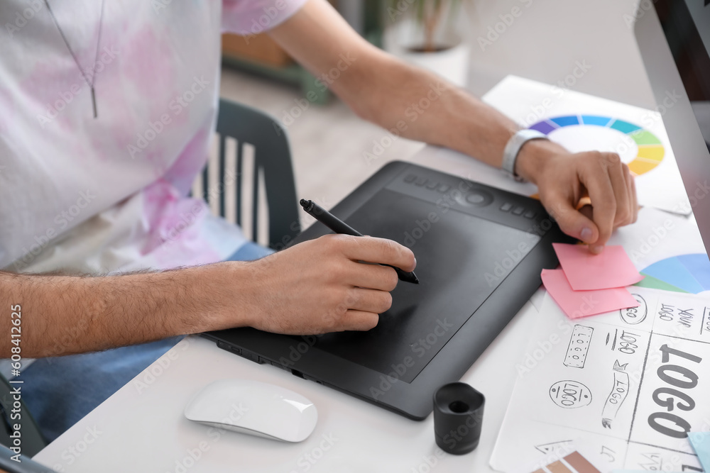 Male graphic designer working with tablet at table in office, closeup