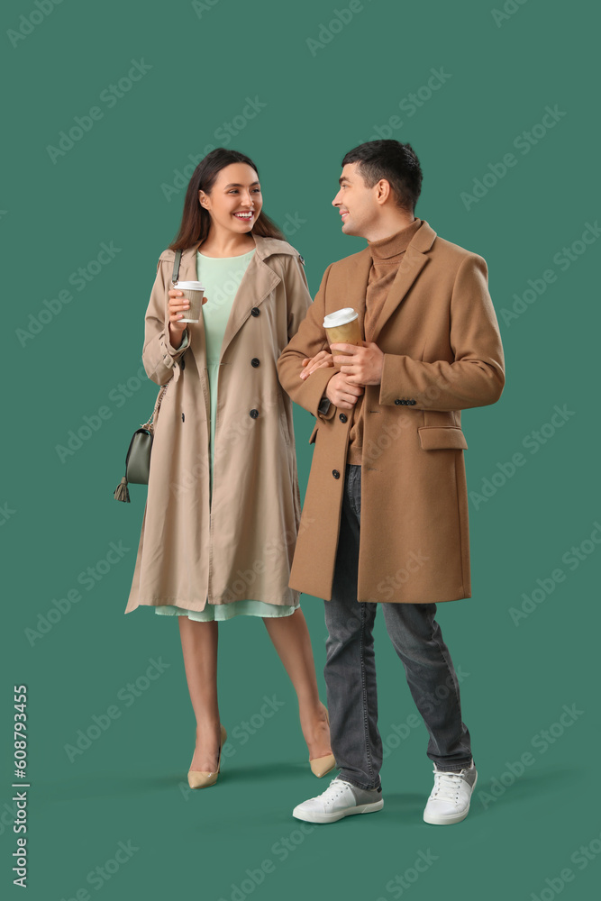 Lovely young couple with cups of coffee on green background