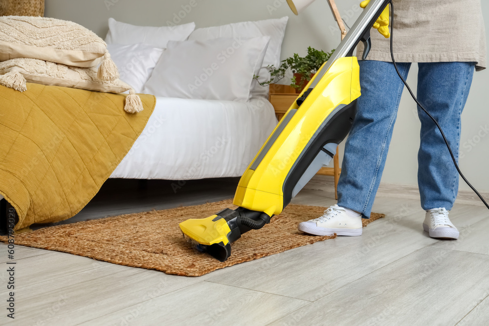 Housewife hoovering carpet in bedroom