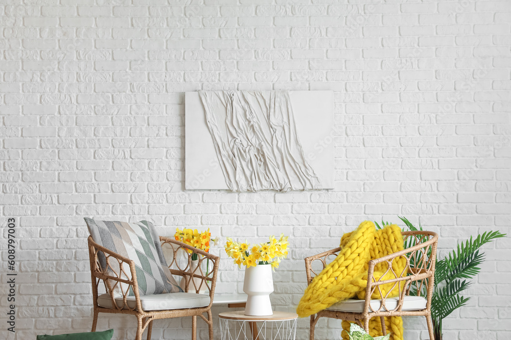 Interior of living room with cozy armchairs and blooming narcissus flowers on coffee table