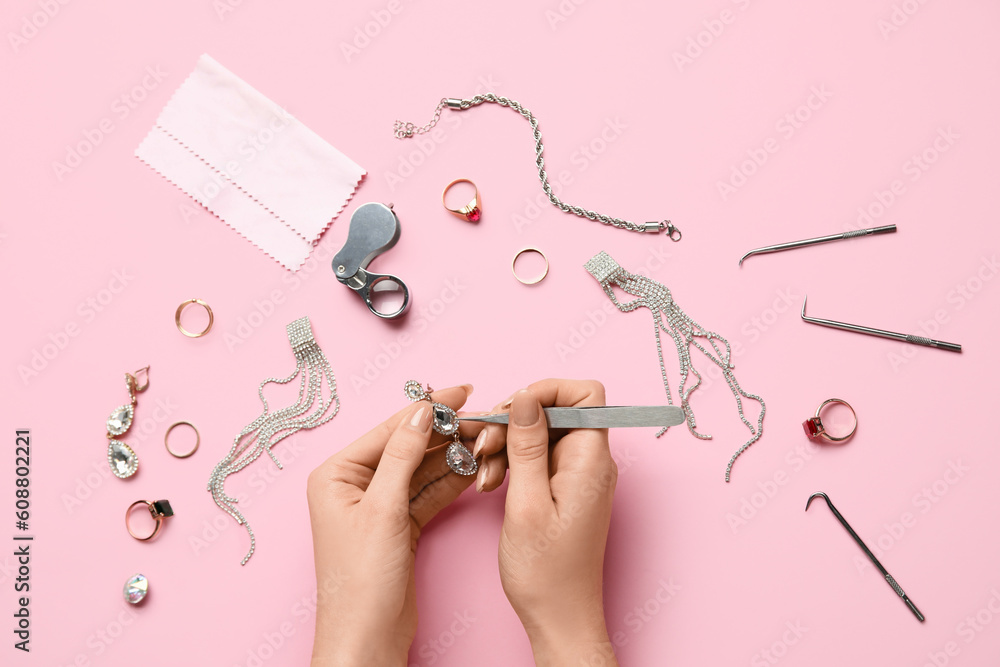 Woman cleaning beautiful jewelry on pink background