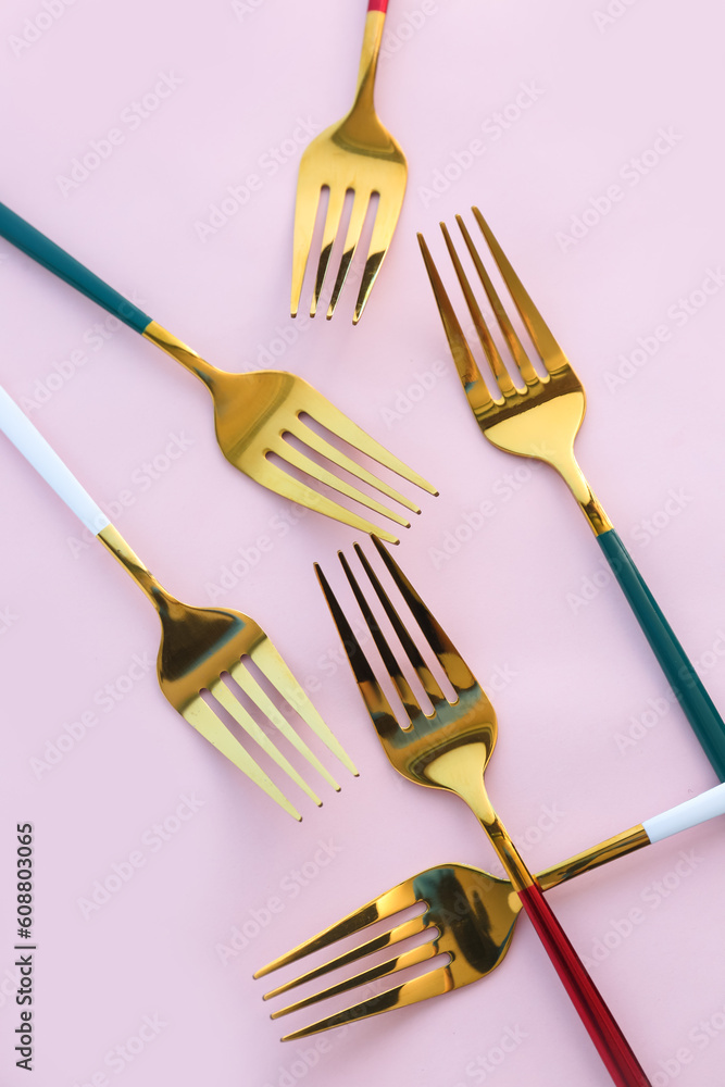 Golden forks on pink background