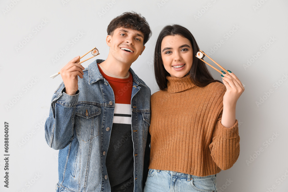 Young couple with sushi on light background