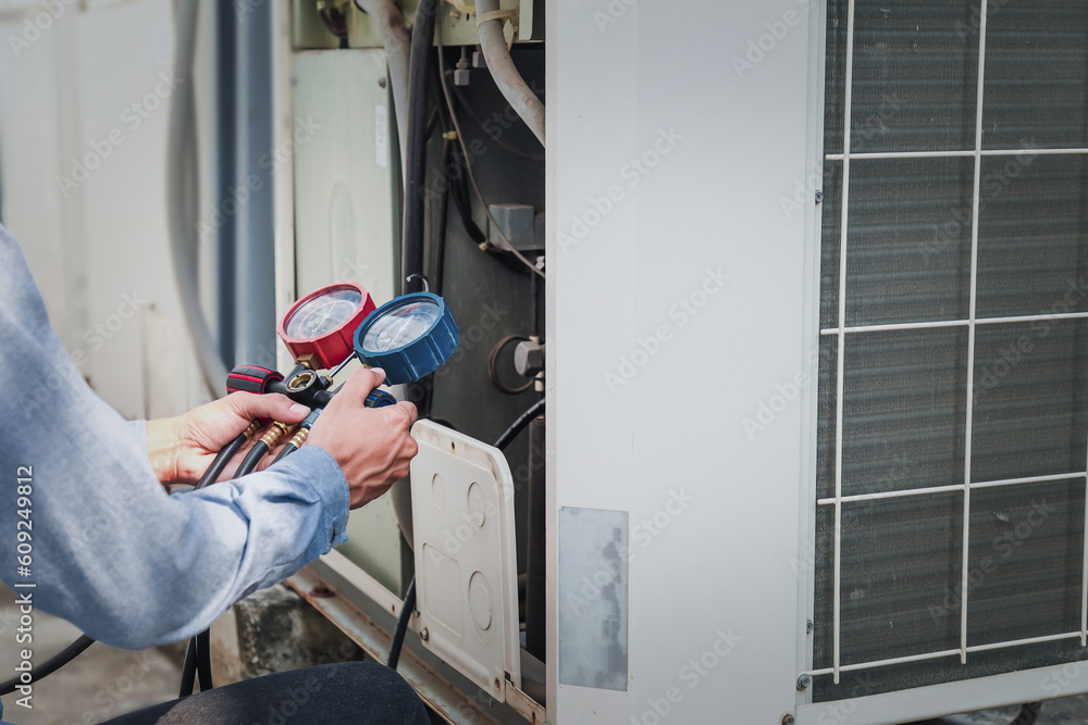 Mechanic  air conditioner technician is using a manifold gauge to check the refrigerant in the syste