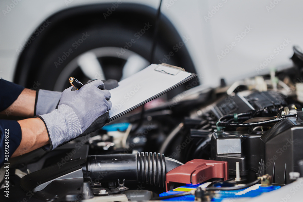 Professional mechanic working on the engine of the car in the garage. Car repair service.