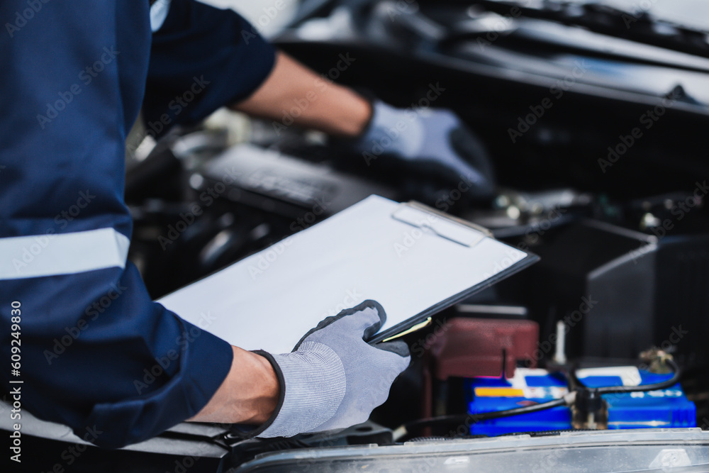 Professional mechanic working on the engine of the car in the garage. Car repair service.